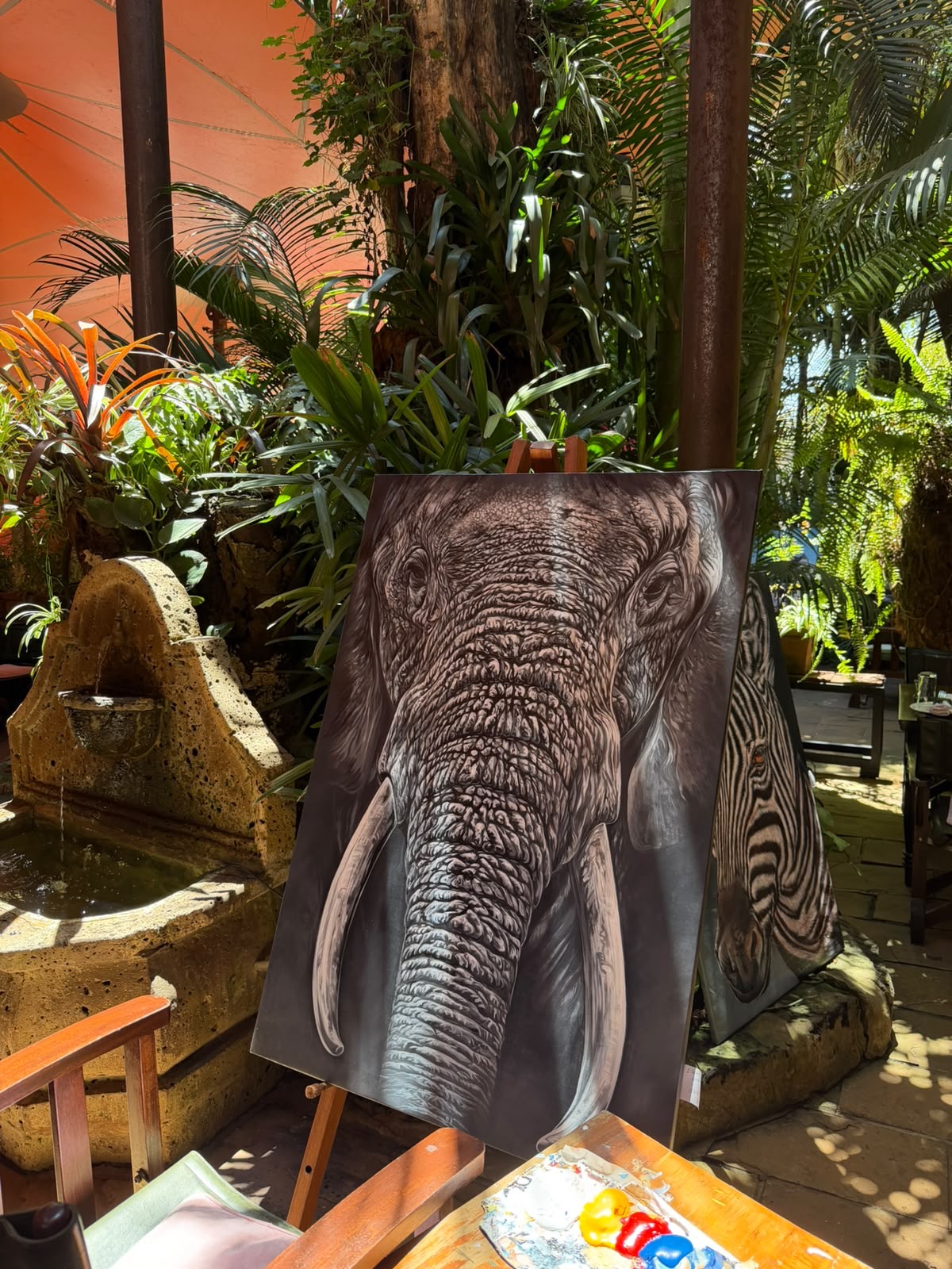 An elephant portrait on an easel beside the garden fountain