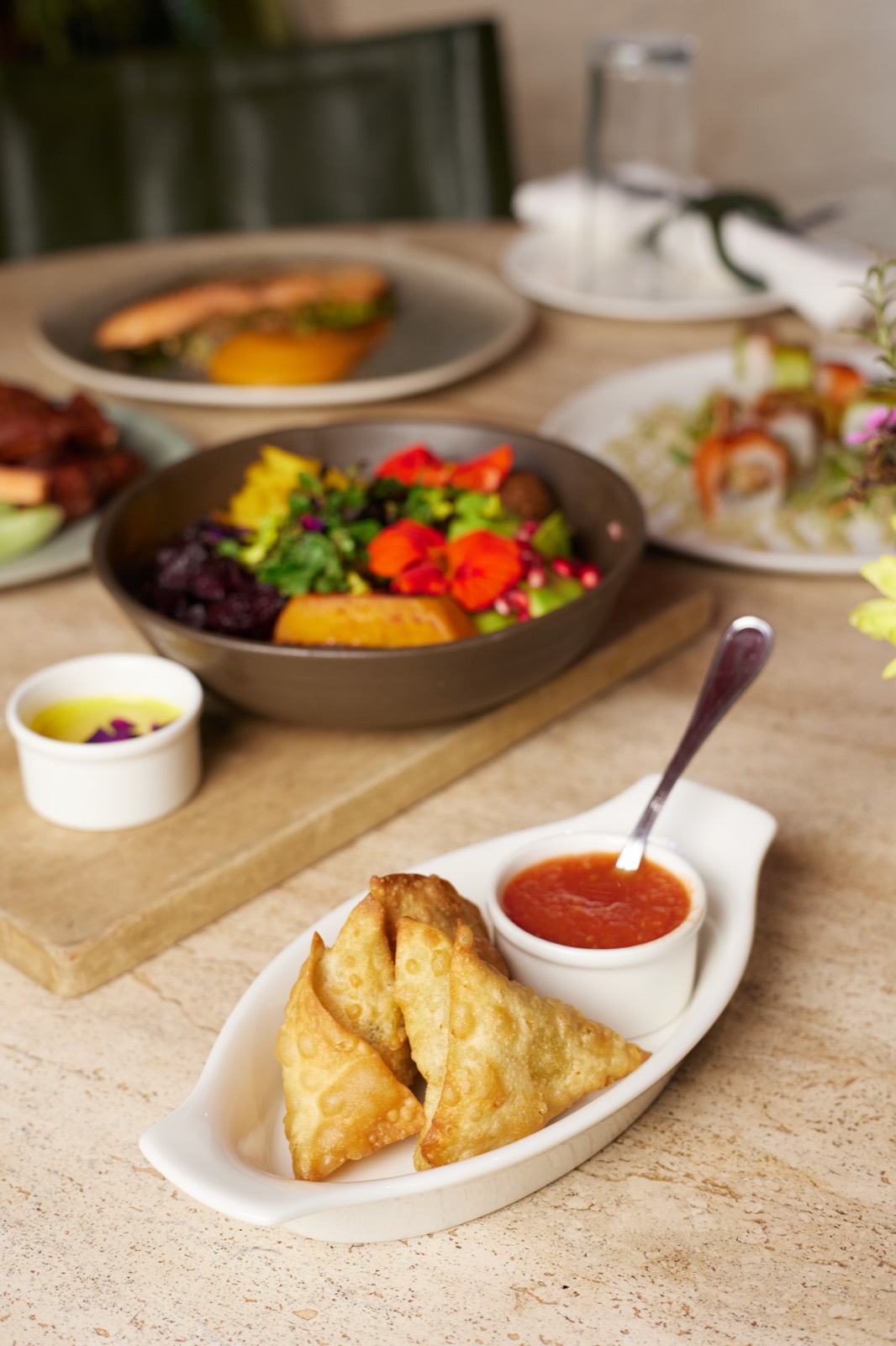 A garden bowl and warm samosas set out on wood